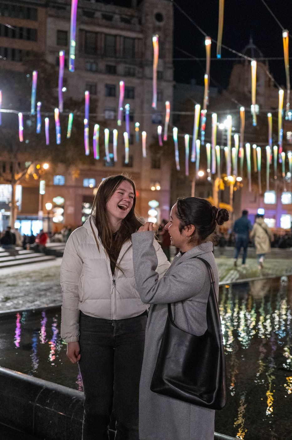 Passersby under string lights at night, Barcelona