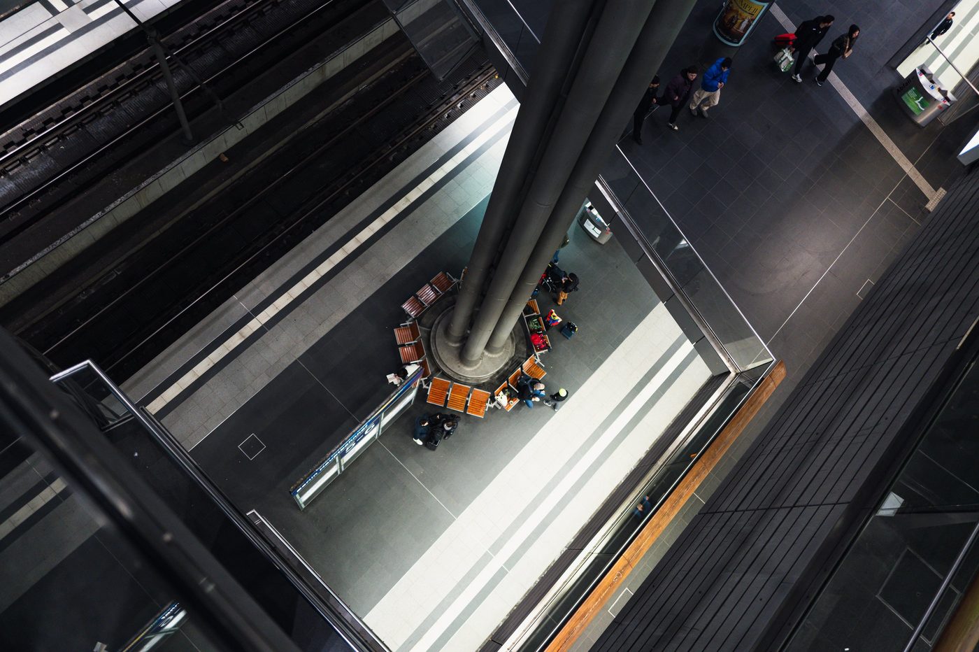 High-angle view of a station platform and a central pillar surrounded by travelers, Berlin