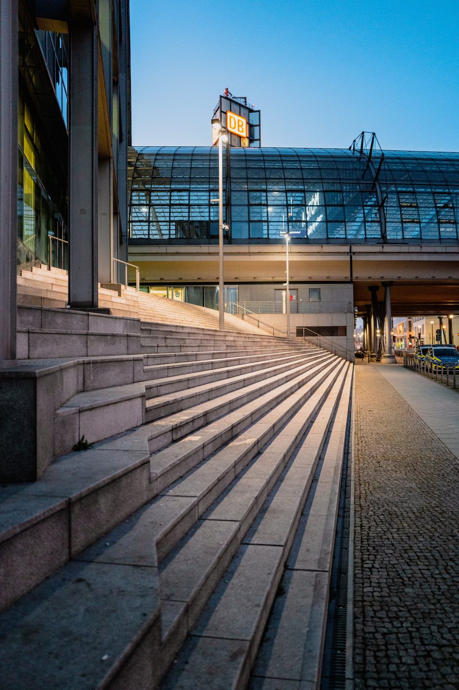 Stone staircase rising toward the illuminated central station at dusk, Berlin