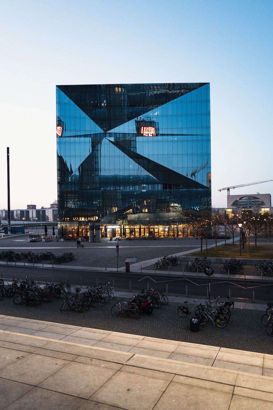 Triangulated glass facade of a cubic building above parked bicycles, Berlin