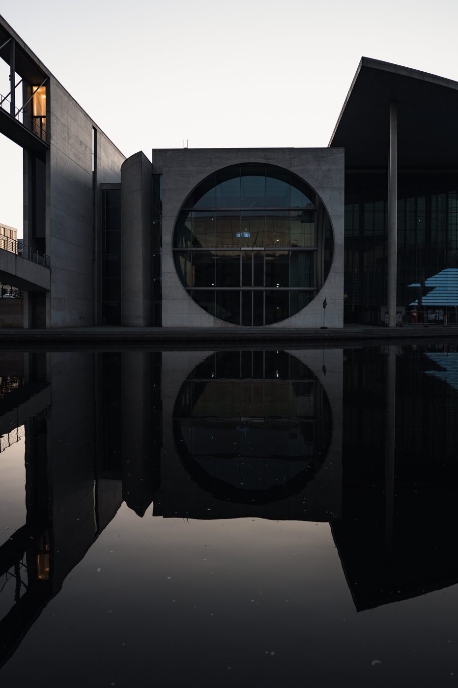 Circular window of a government building reflected in the water at dusk, Berlin
