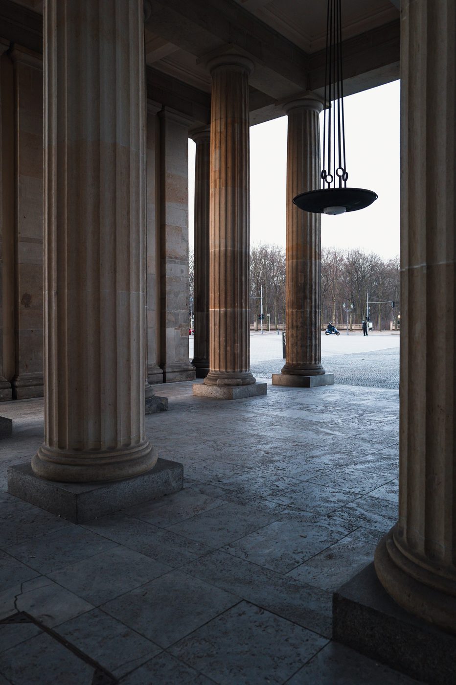 Stone colonnade and hanging lantern beneath the portico of the Brandenburg Gate, Berlin