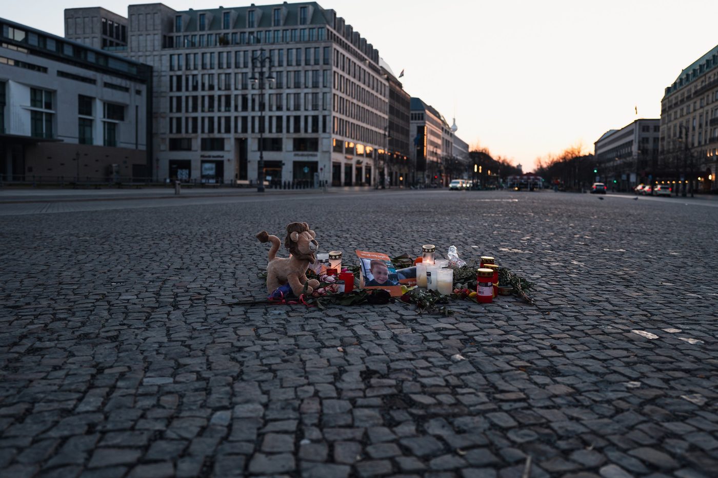 Candles, flowers, and a stuffed toy left on the cobblestones of a square, Berlin