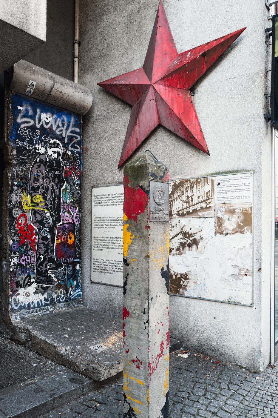 Section of the Berlin Wall covered in graffiti beside a red star, Berlin