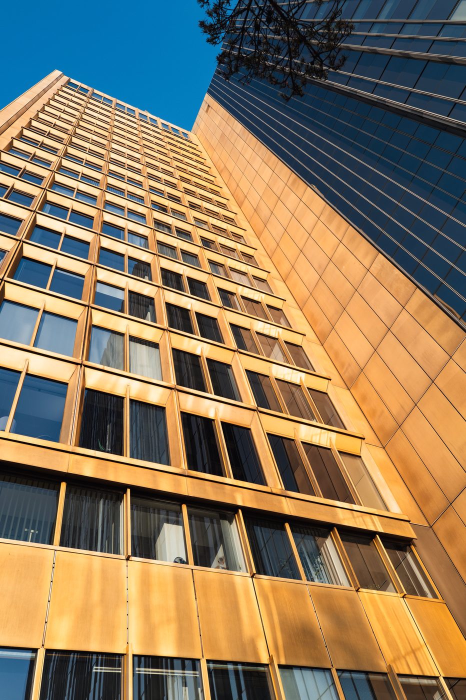Two golden towers converging toward a corner of blue sky, Berlin