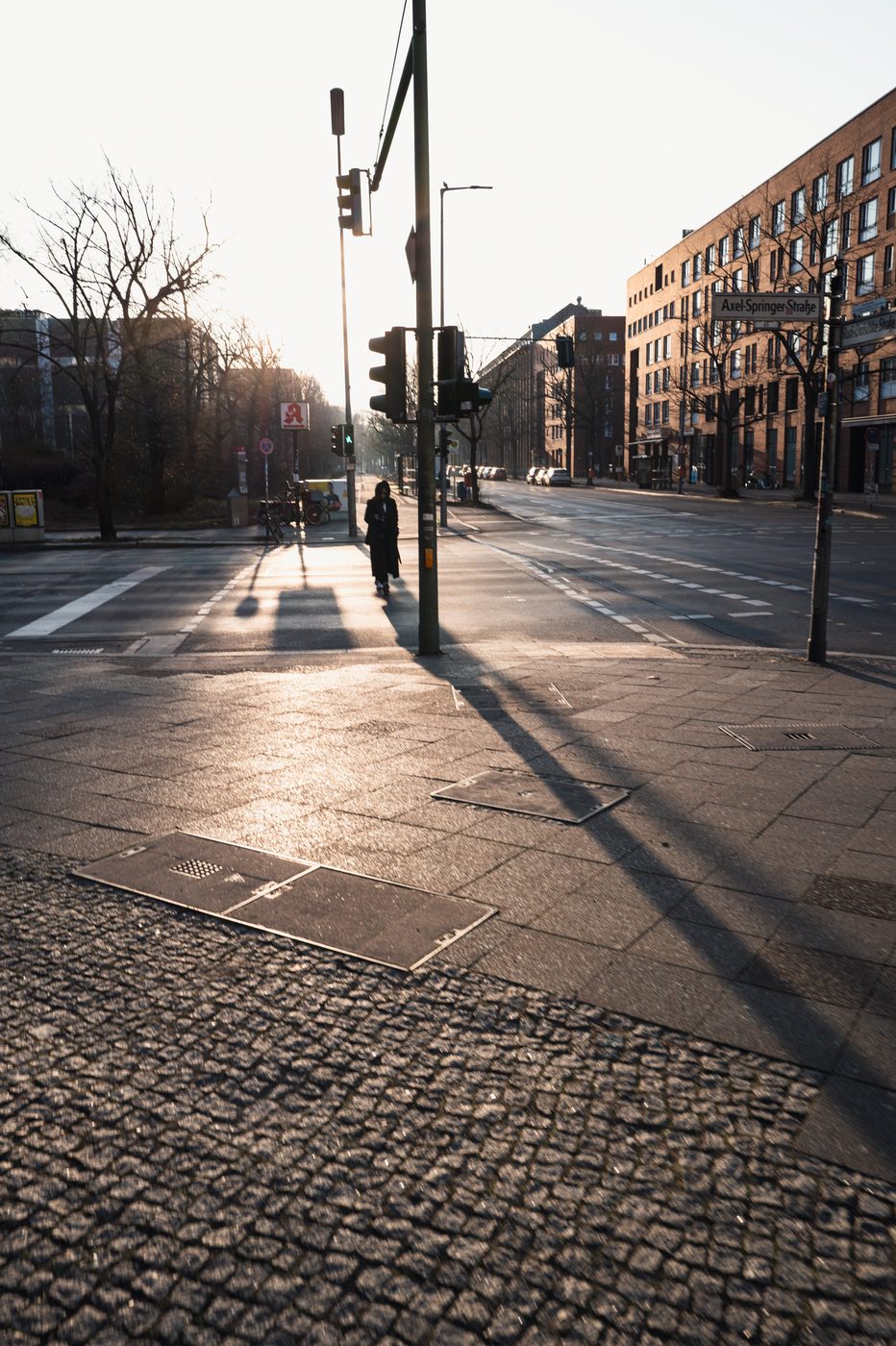 Backlit passerby casting a long shadow on the cobblestones, Berlin