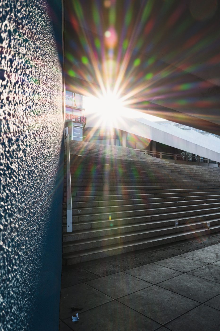 Burst of sunlight filtering between two facades above a staircase, Berlin