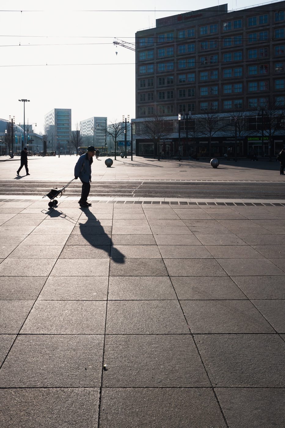 Man pulling a wheeled cart across Alexanderplatz, Berlin