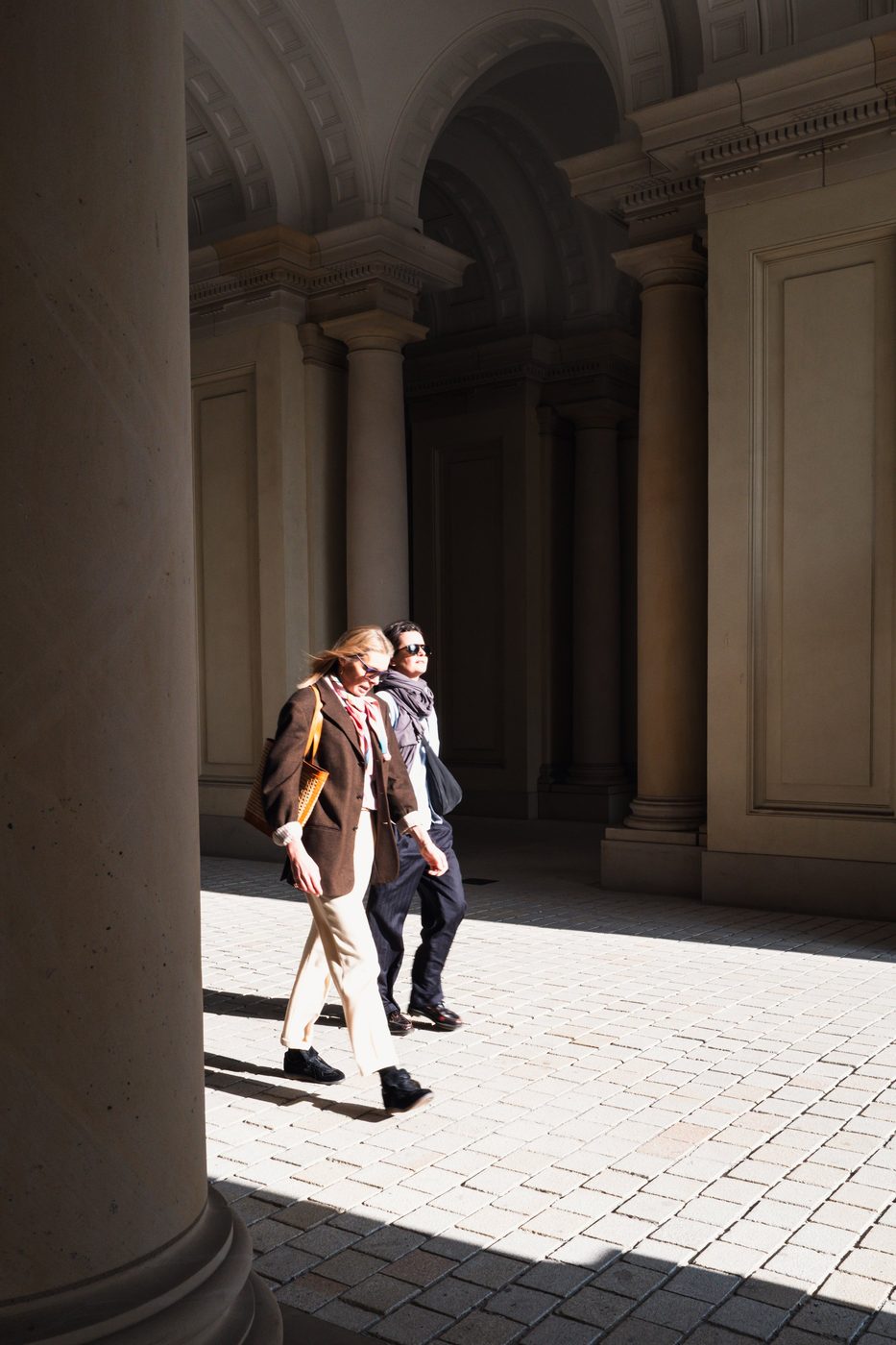 Couple crossing a colonnade in chiaroscuro, a play of shadow and light, Berlin