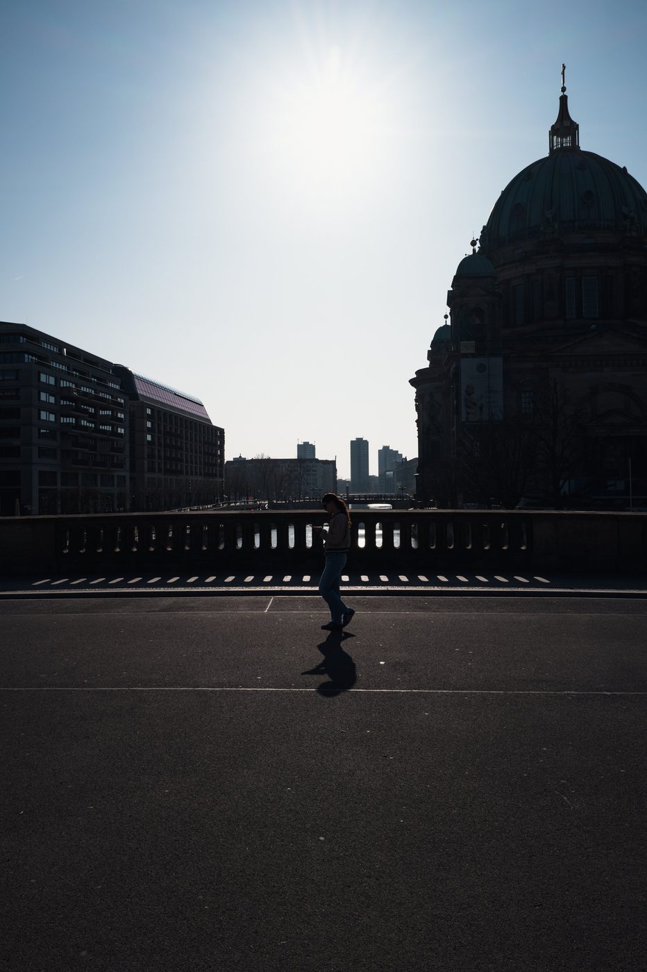 Backlit woman crossing a bridge facing Berlin Cathedral, Berlin