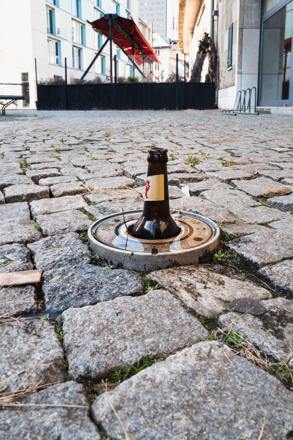 Beer bottle wedged in a manhole cover between the cobblestones, Berlin
