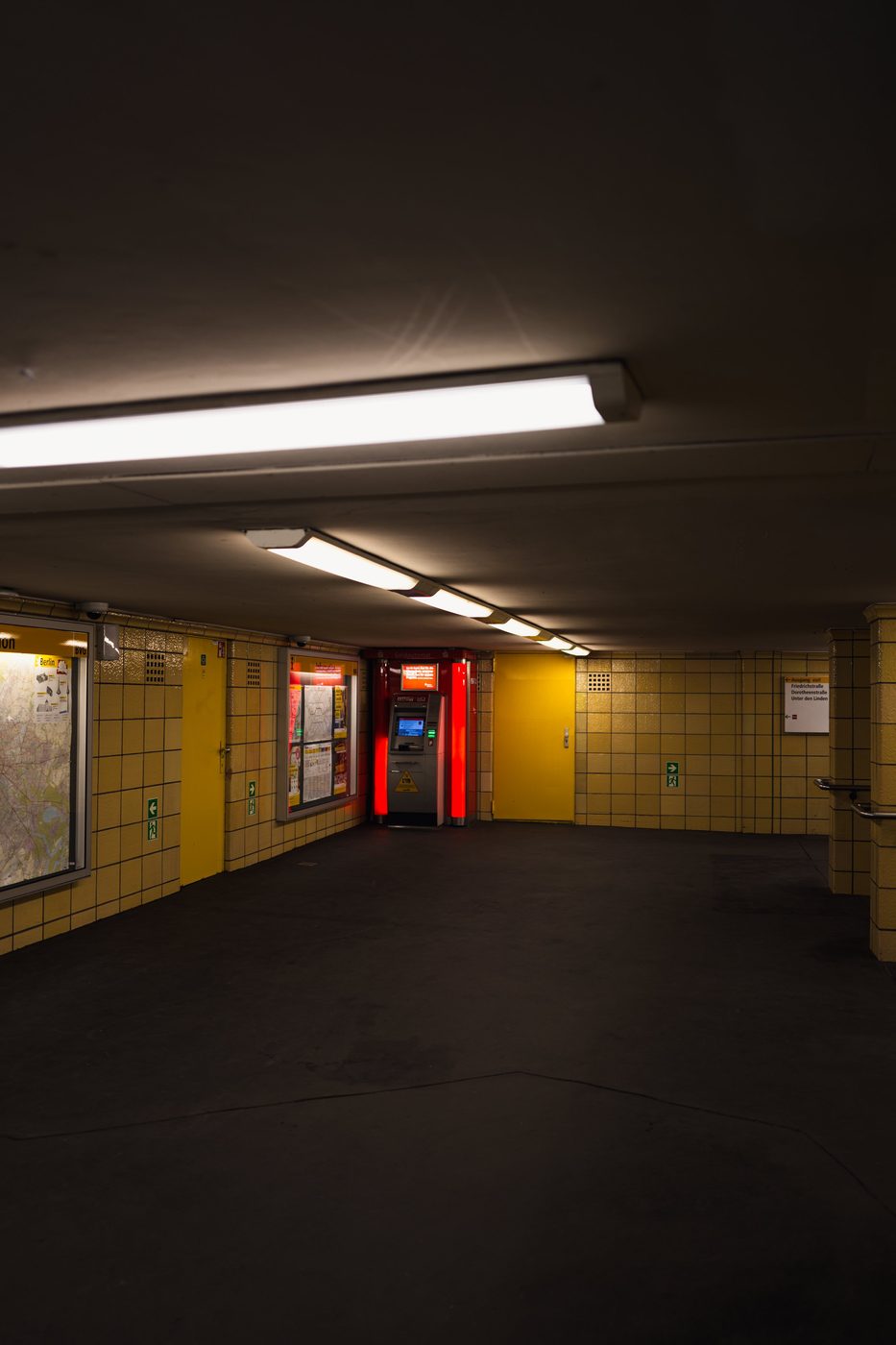 Yellow-tiled underground corridor leading toward an illuminated vending machine, Berlin