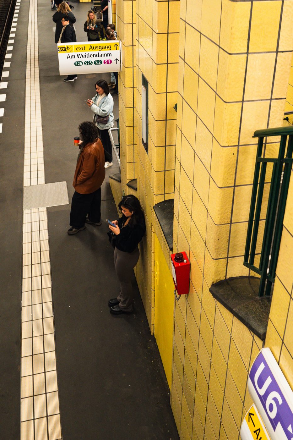 High-angle view of a subway platform and travelers absorbed in their phones, Berlin