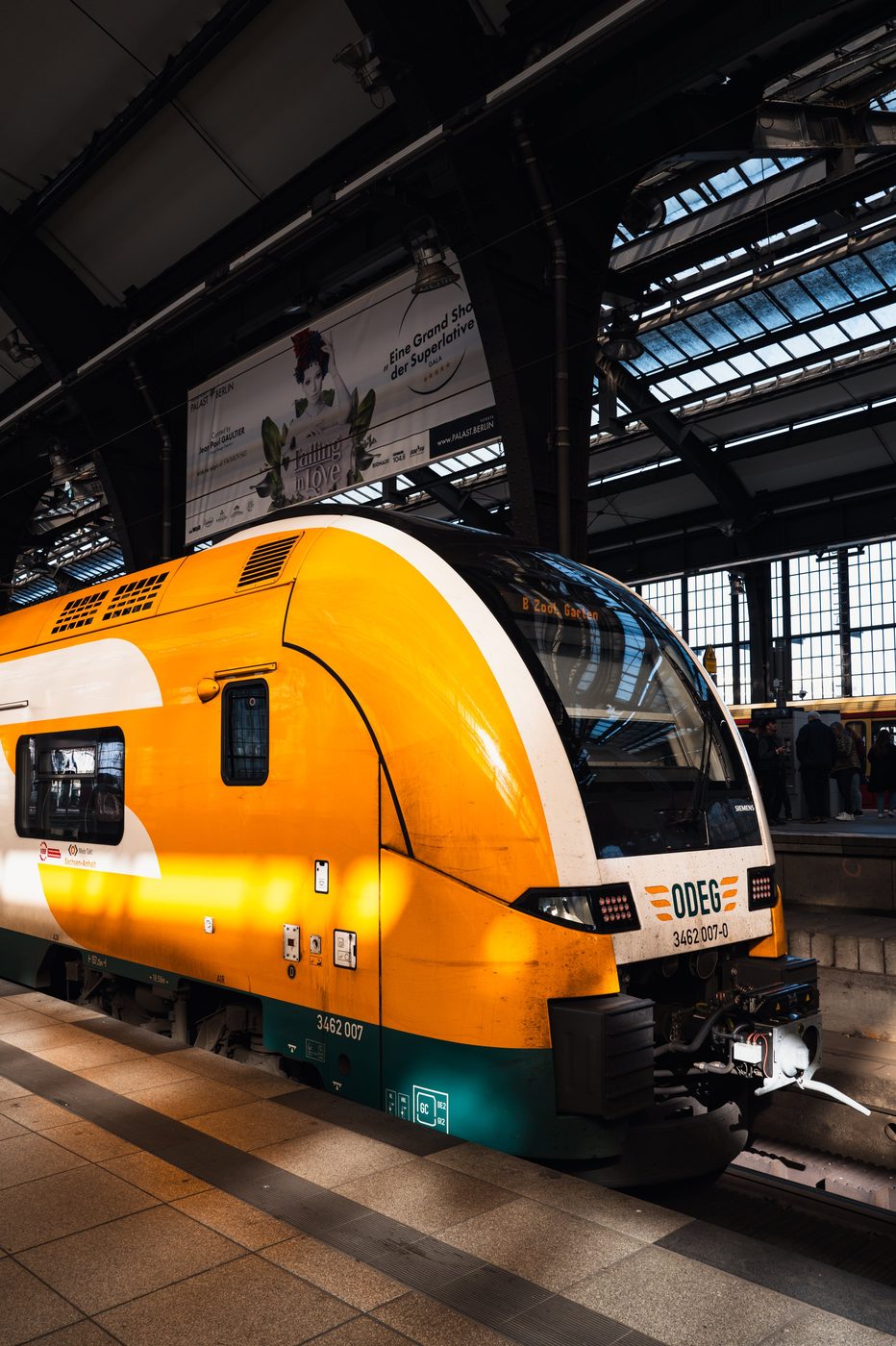 Orange and white regional train at the platform beneath the station's glass roof, Berlin