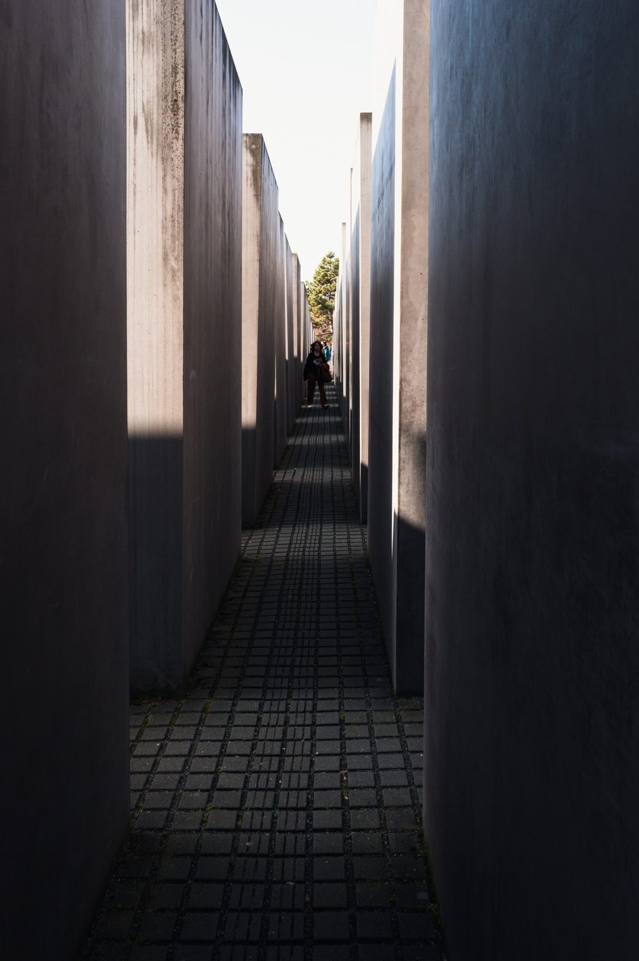 Lone silhouette at the end of a corridor between the memorial's slabs, Berlin