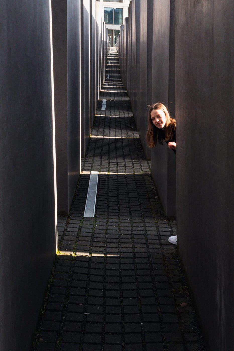 A curious child peeking between the slabs of the memorial, Berlin