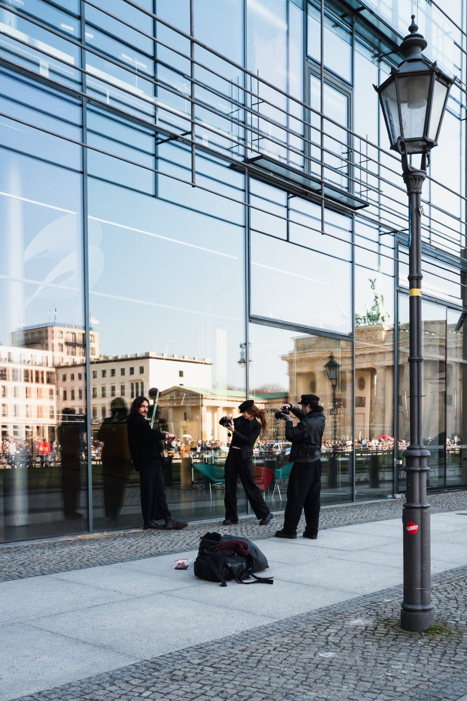 Street musicians reflected in a glass facade near the Brandenburg Gate, Berlin