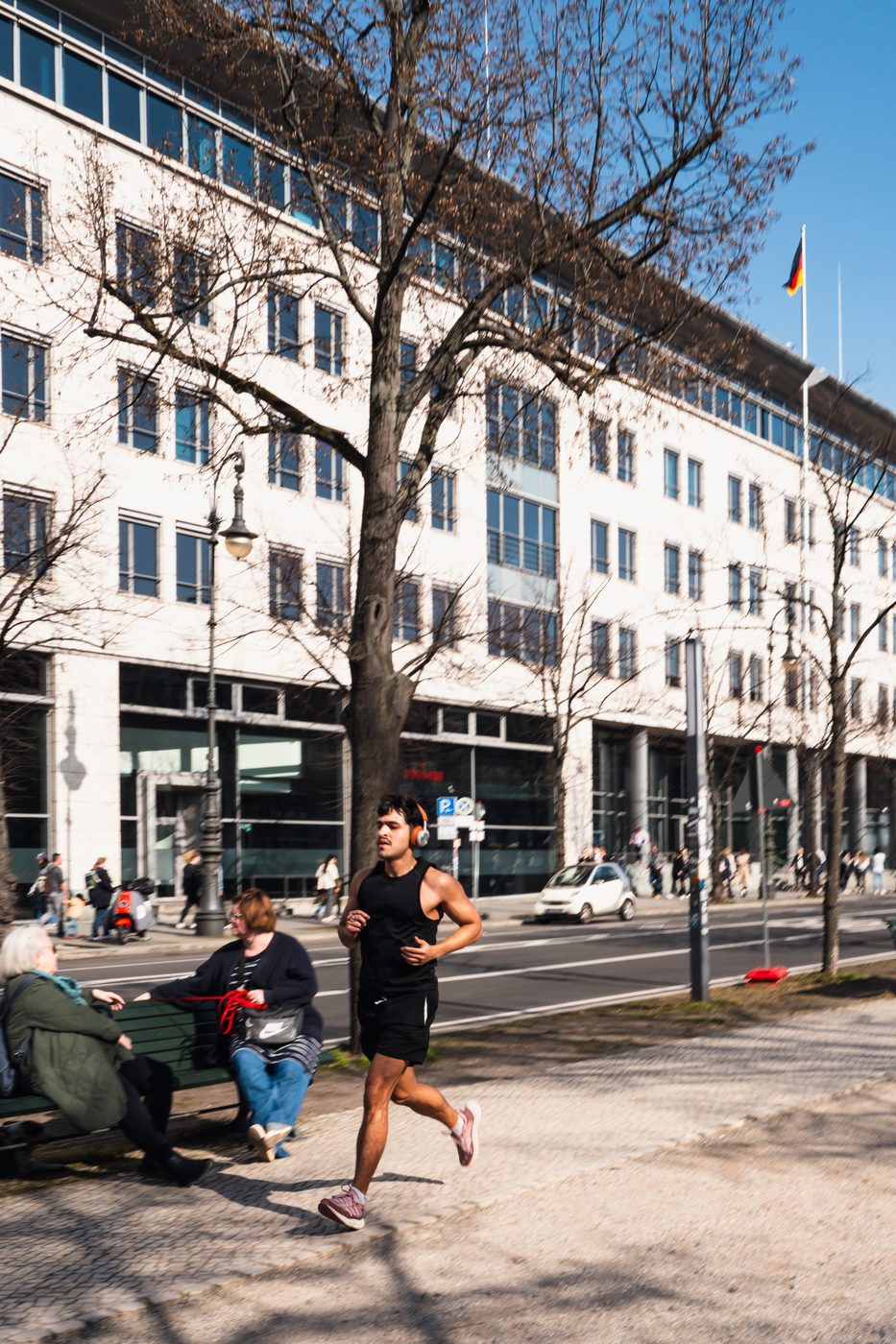 Runner passing a bench and a government building, Berlin