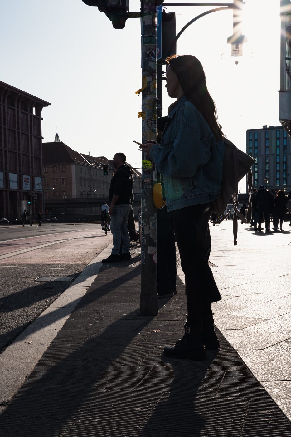 Backlit woman waiting at a traffic light, wearing a denim jacket, Berlin