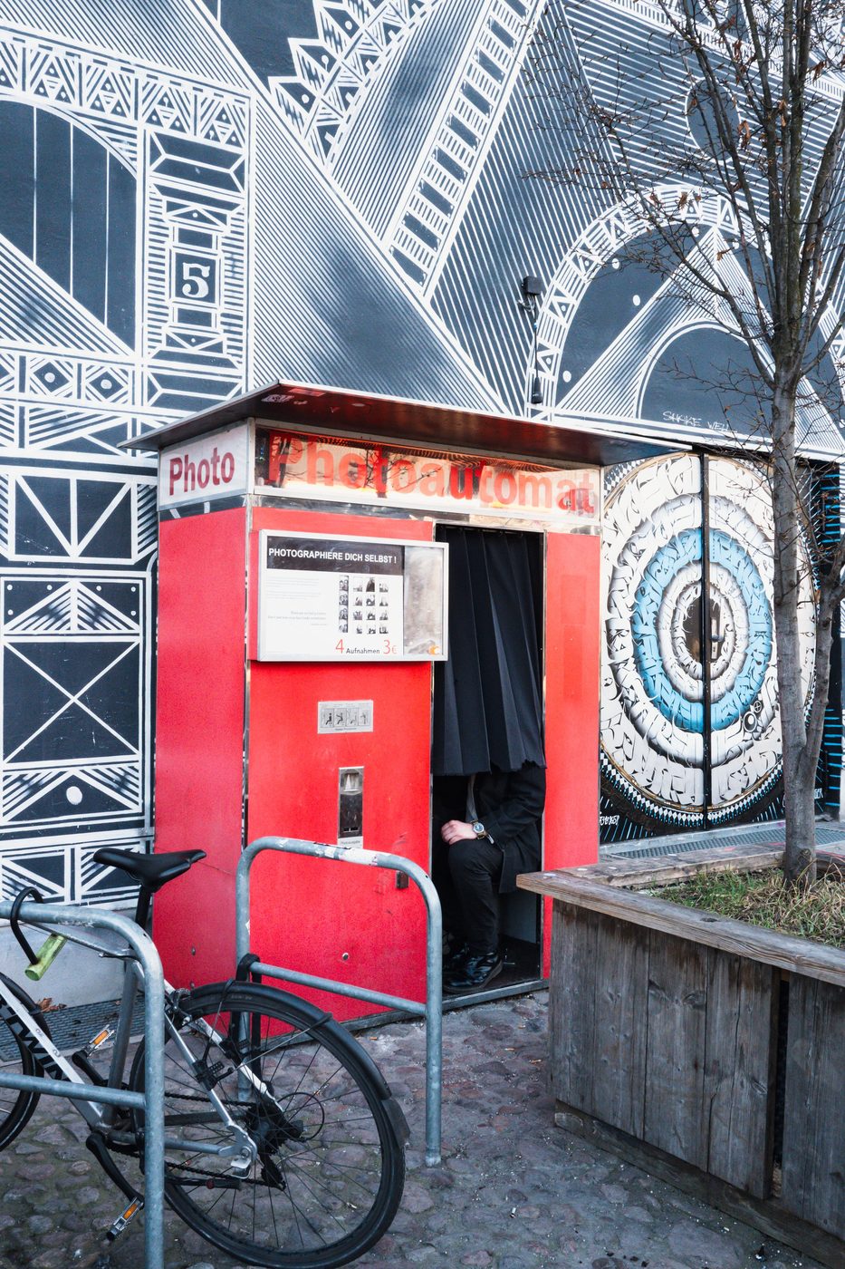 Red photo booth in front of a geometric mural, Berlin