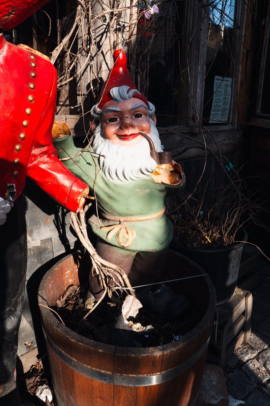 Garden gnome smoking a pipe beside a red soldier statue, Berlin