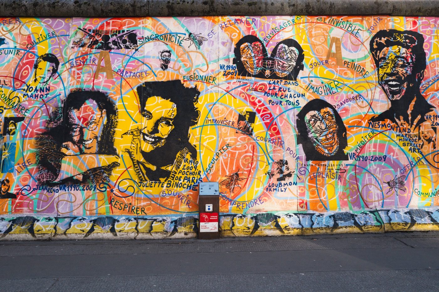 Colorful mural at the East Side Gallery blending painted portraits with inspiring words, Berlin