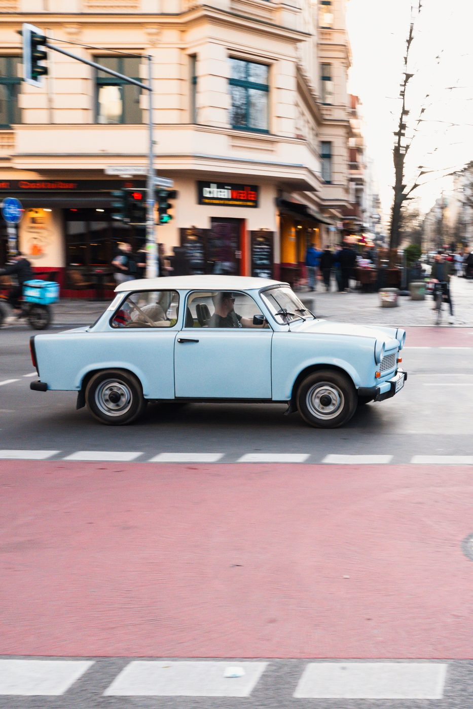 Sky-blue Trabant crossing an intersection with red road markings, Berlin