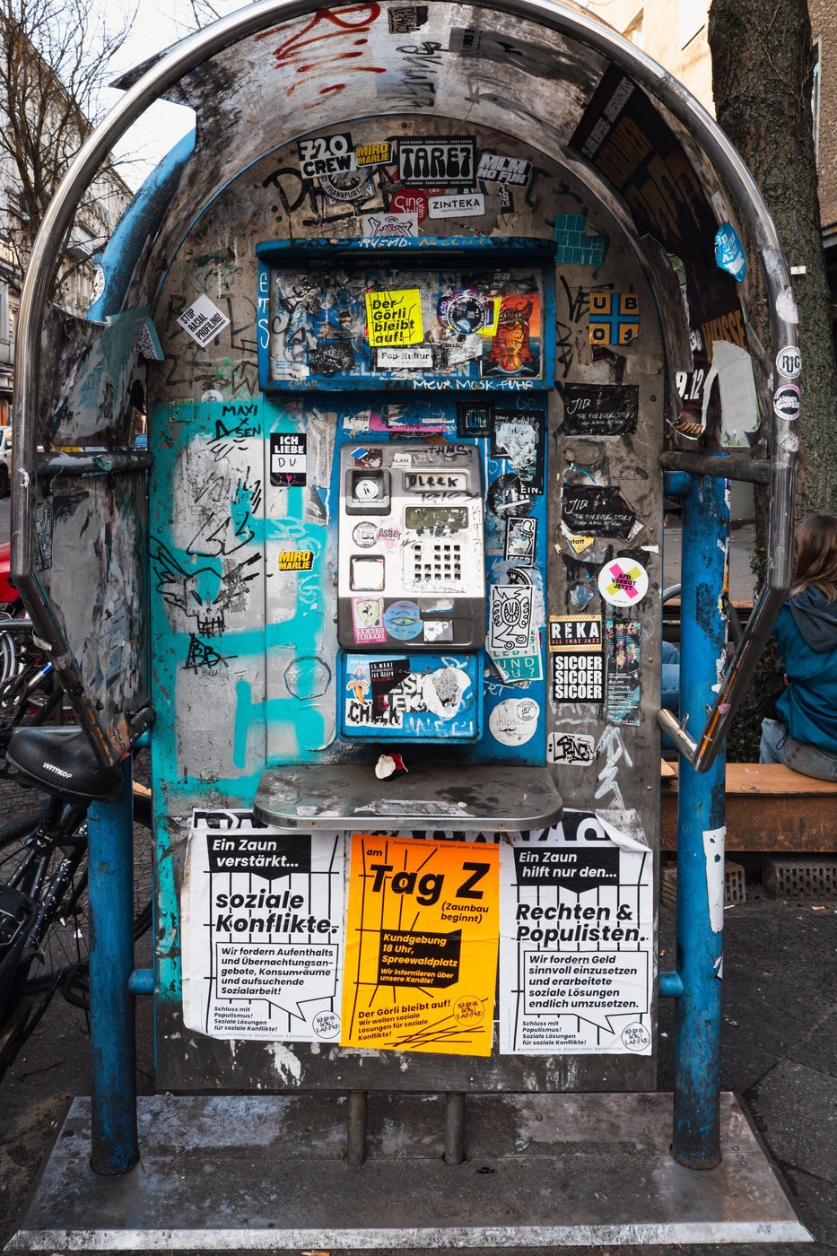 Old metal phone booth covered in stickers and posters, Berlin