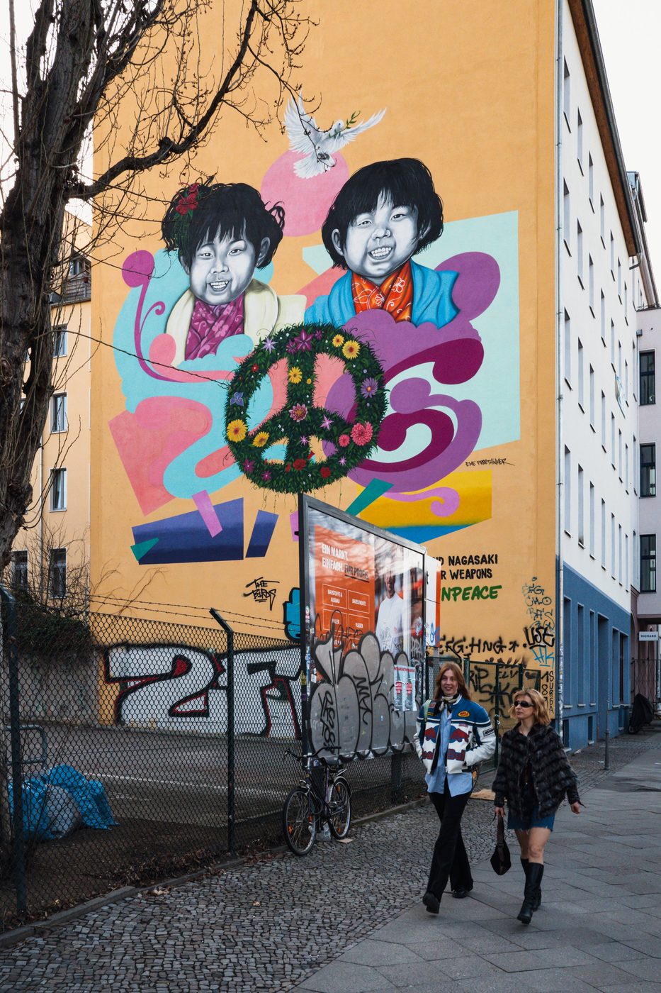 Mural of two smiling children framing a flower-adorned peace symbol, Berlin