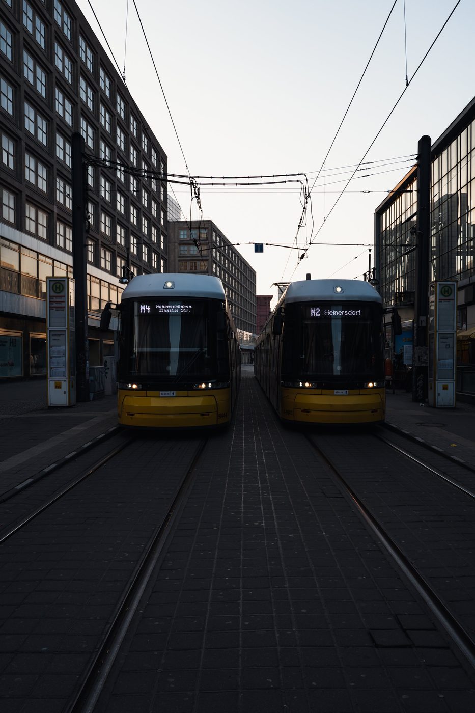 Two yellow trams facing each other symmetrically between buildings, Berlin