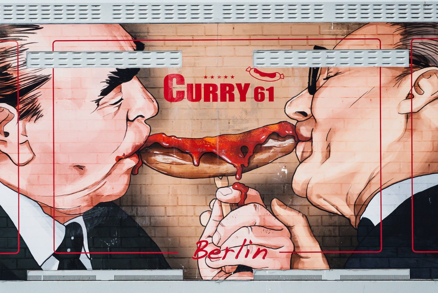 Humorous mural of two men sharing a currywurst dripping with sauce, Berlin
