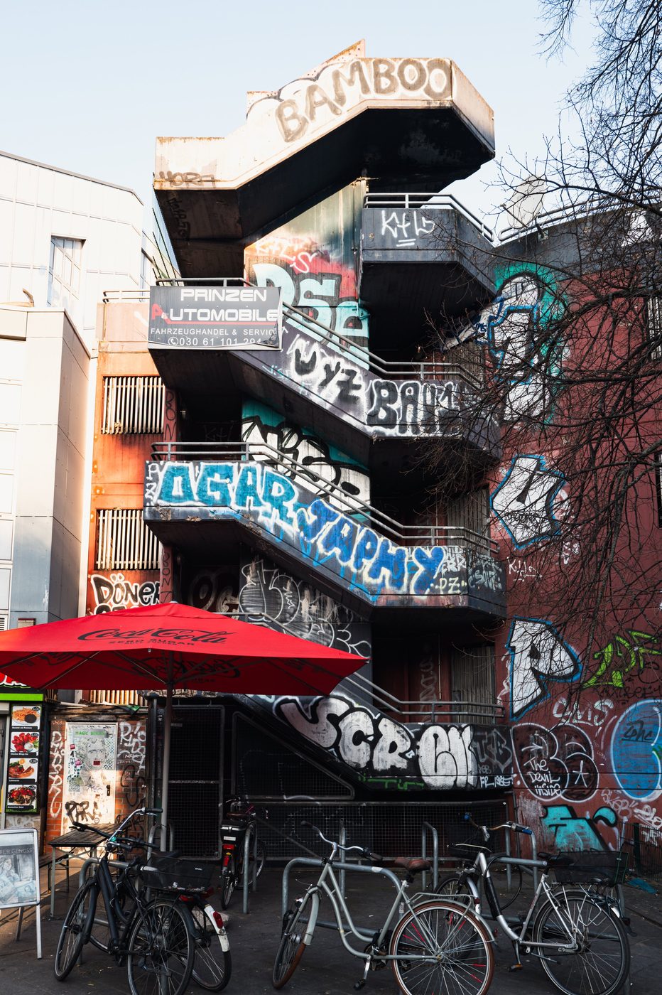 Metal fire escape striped with graffiti above parked bicycles, Berlin