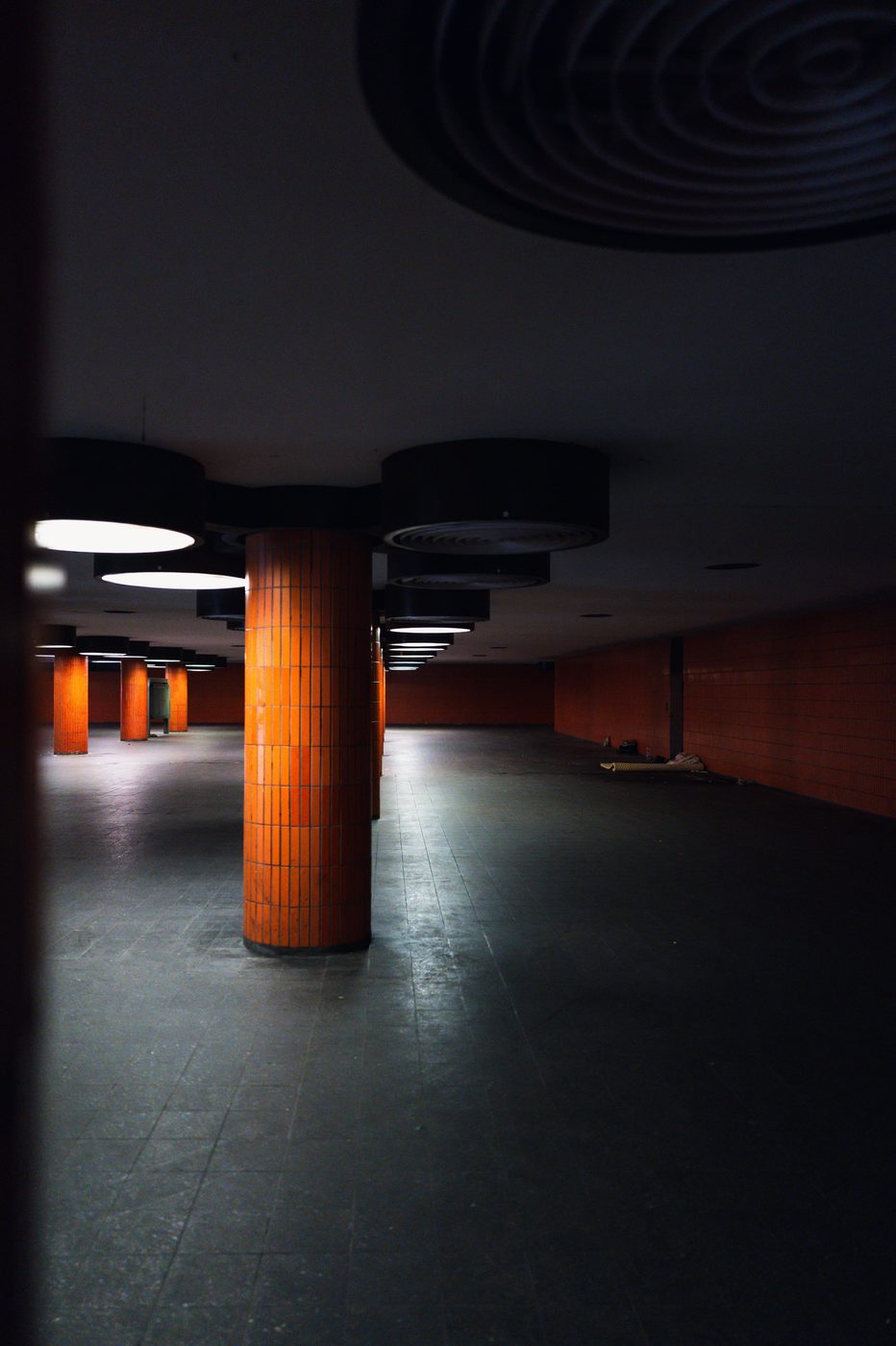 Row of orange-tiled columns in a deserted underground hall, Berlin