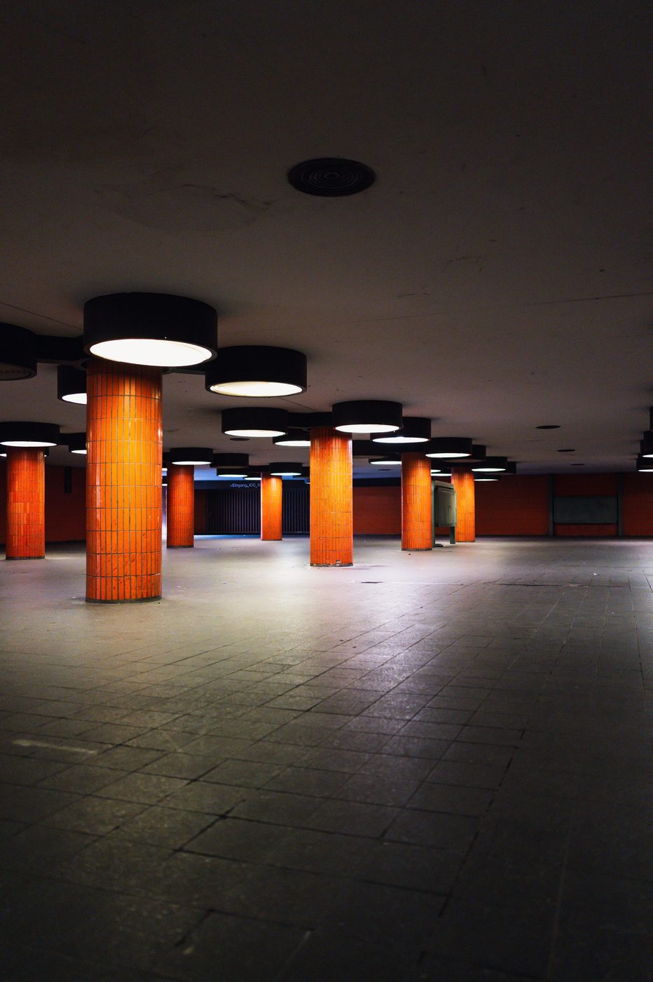 Vast underground hall with orange columns and circular lighting, Berlin