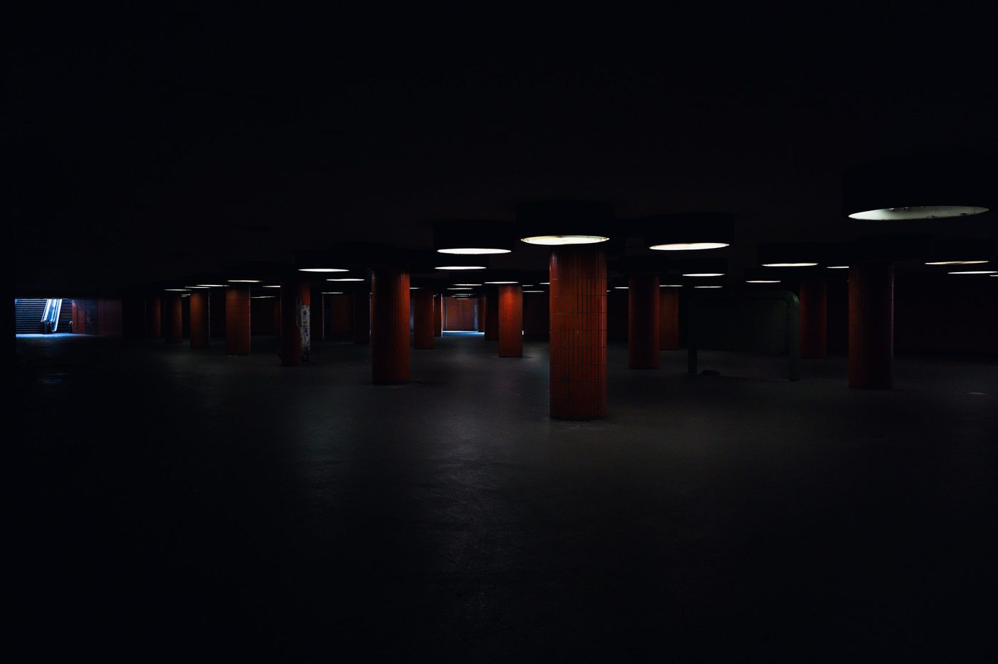 Underground hall shrouded in dimness, columns lit in patches, Berlin