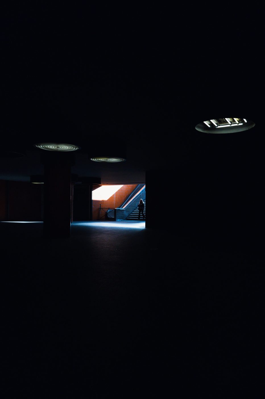 Lone silhouette near a staircase bathed in bluish light, Berlin