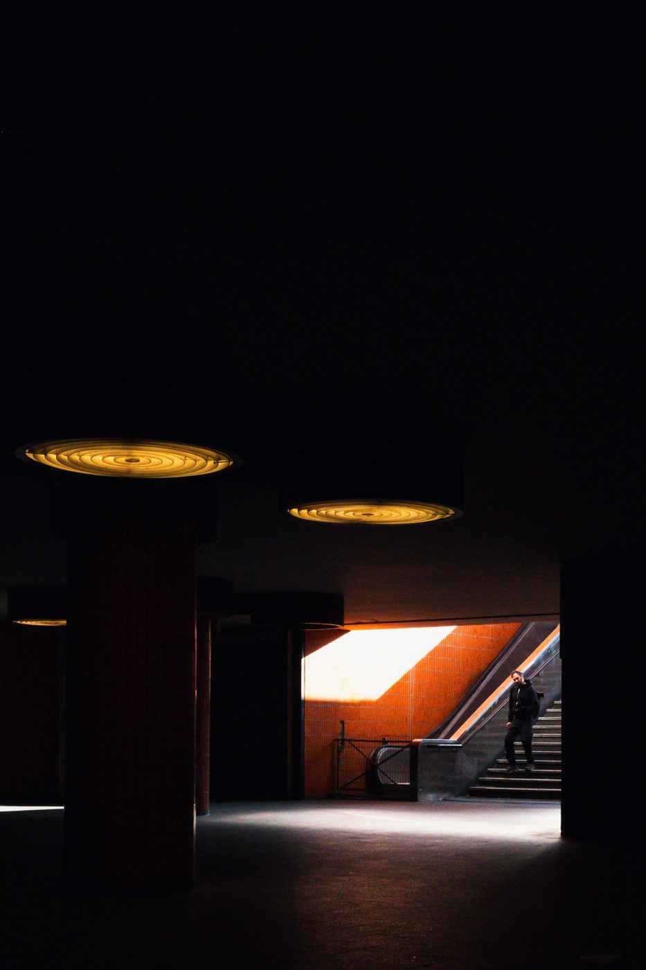 Man descending a staircase in a halo of orange light, Berlin