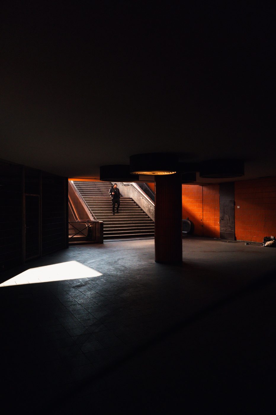 Man lit by a shaft of light at the foot of an underground staircase, Berlin