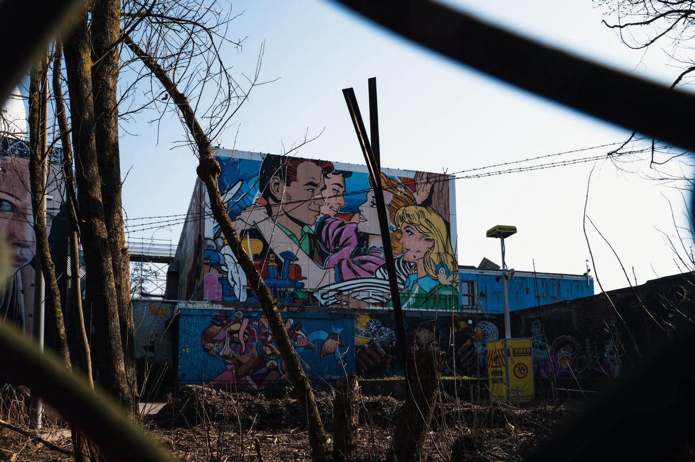 Comic-book style pop art mural seen through barbed wire, Berlin