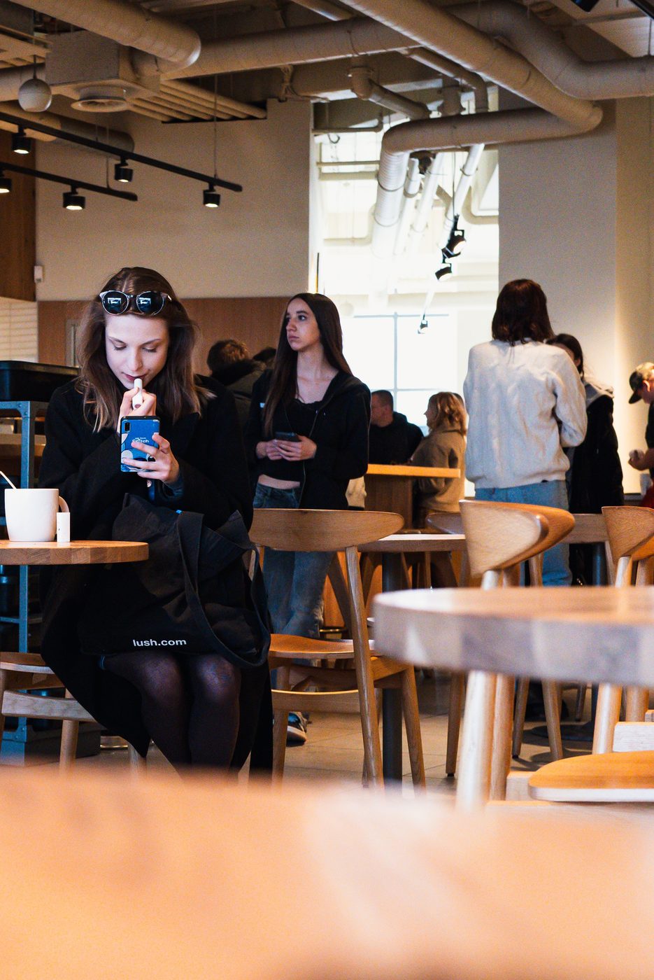 Woman applying lip balm in a bustling cafe, Berlin