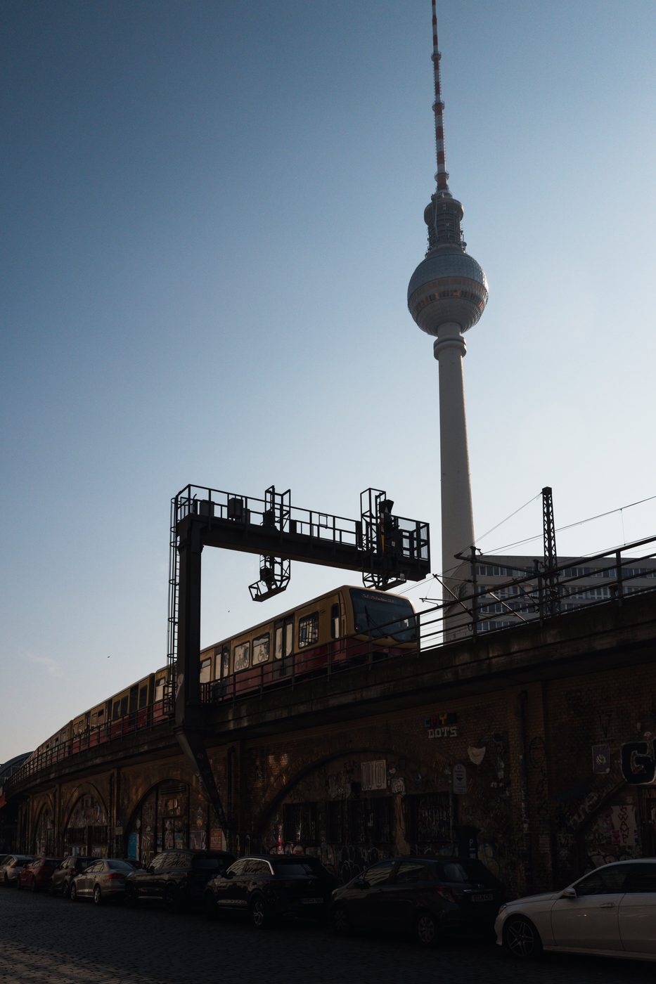 Yellow S-Bahn train passing beneath the television tower, Berlin
