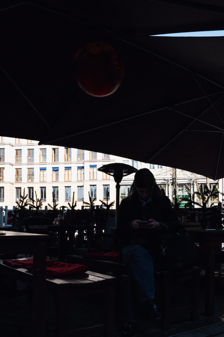 Silhouette of a woman under a parasol, absorbed in her phone, Berlin