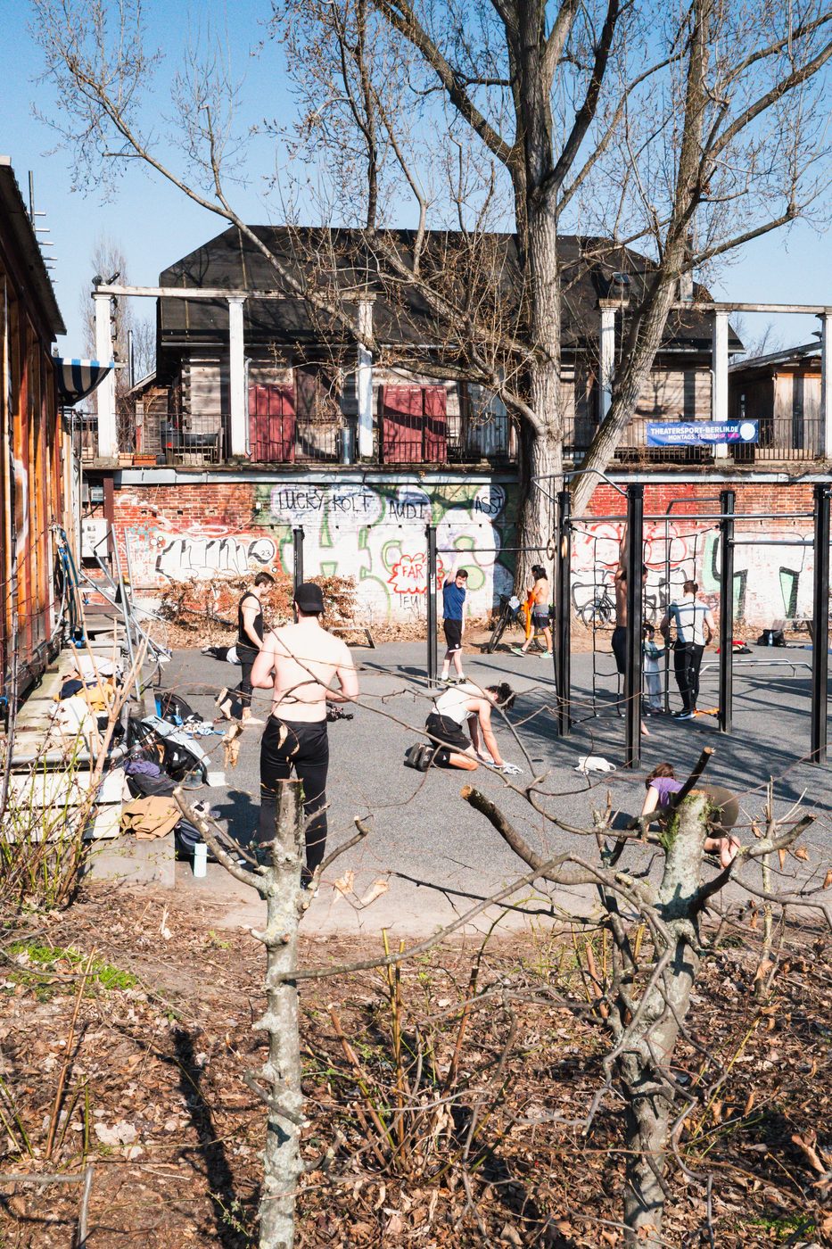 Group of athletes training on parallel bars in front of a graffiti-covered wall, Berlin