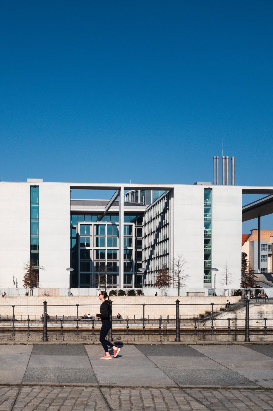 Female runner passing the federal chancellery beneath an intense blue sky, Berlin