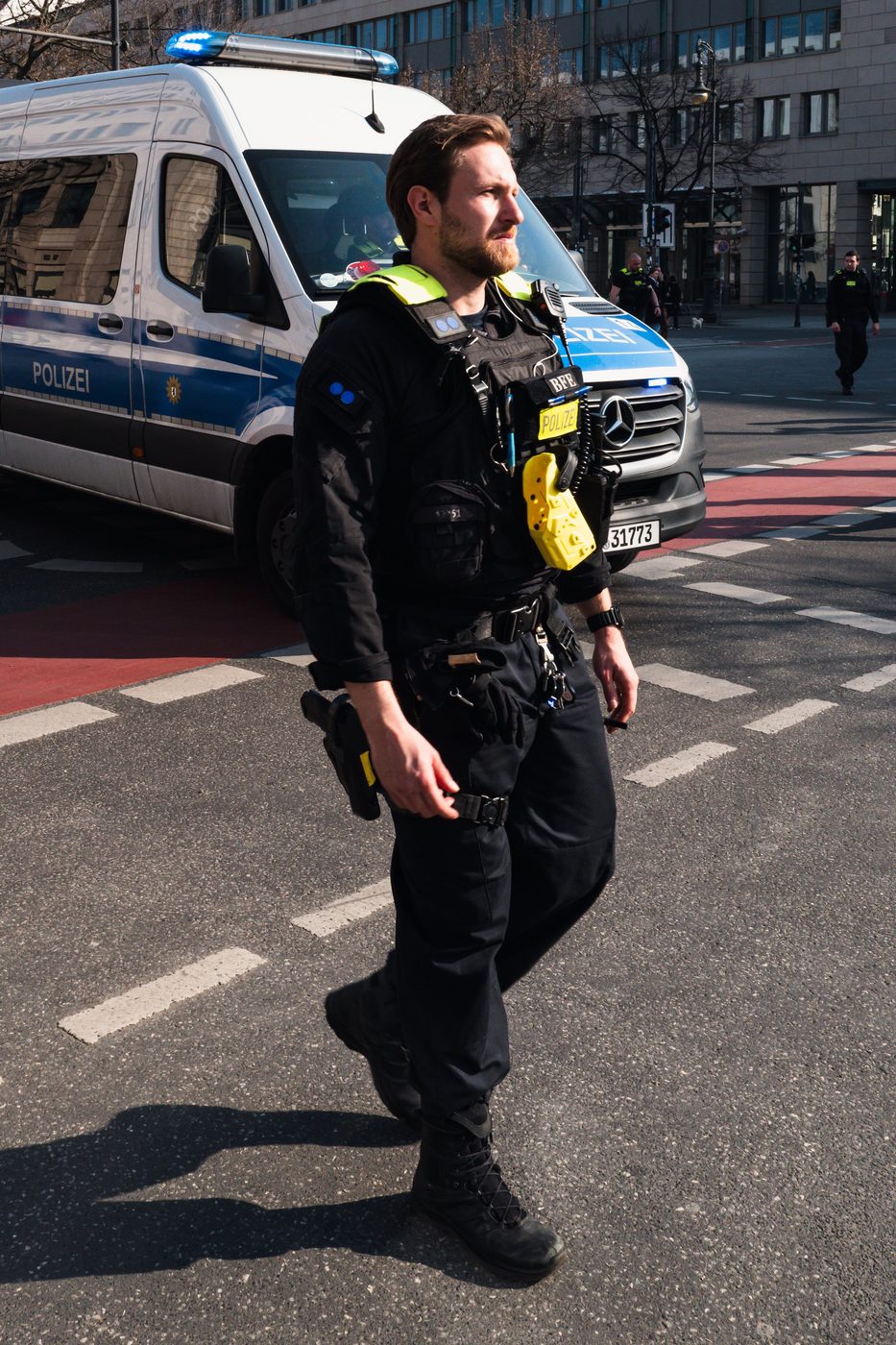 Police officer in tactical gear patrolling in front of a van, Berlin