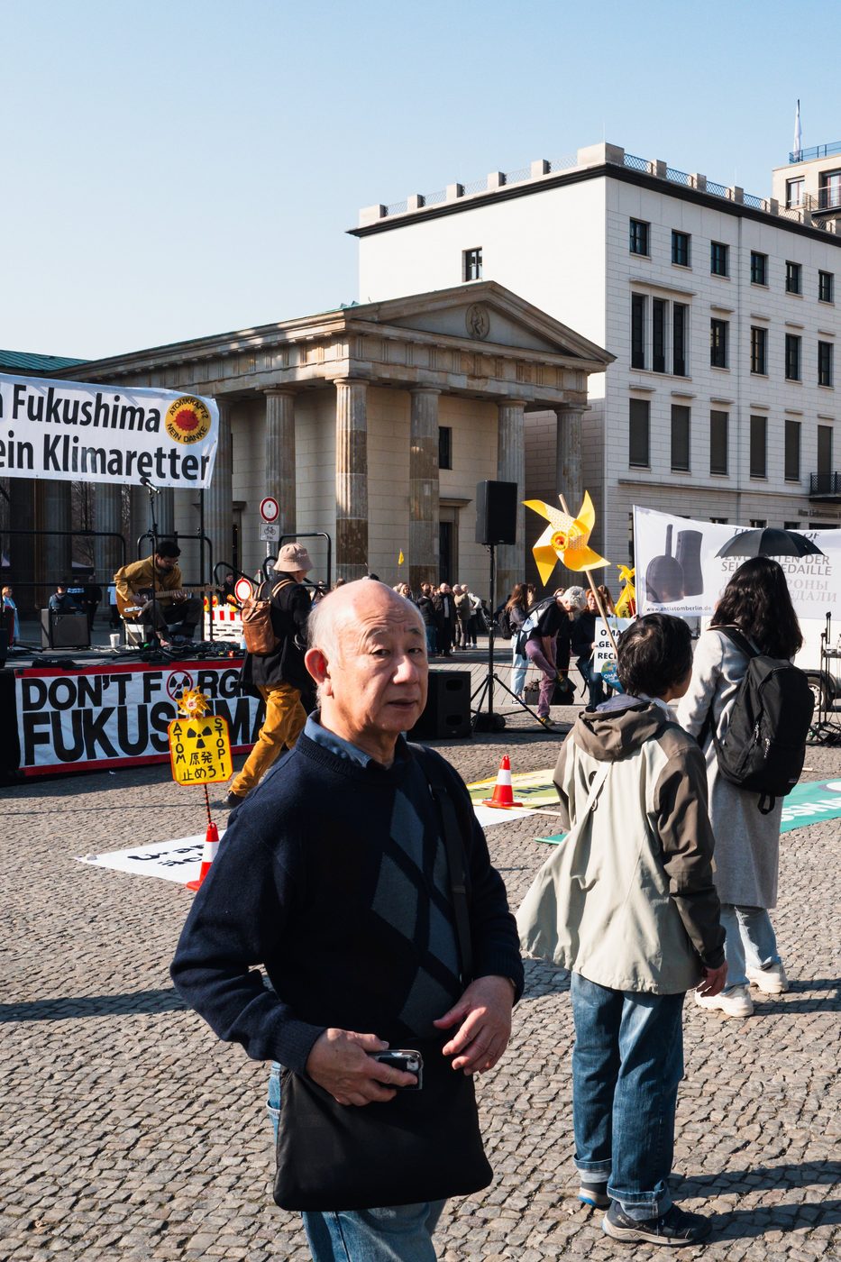 Man in the foreground of an activist gathering in front of the Brandenburg Gate, Berlin