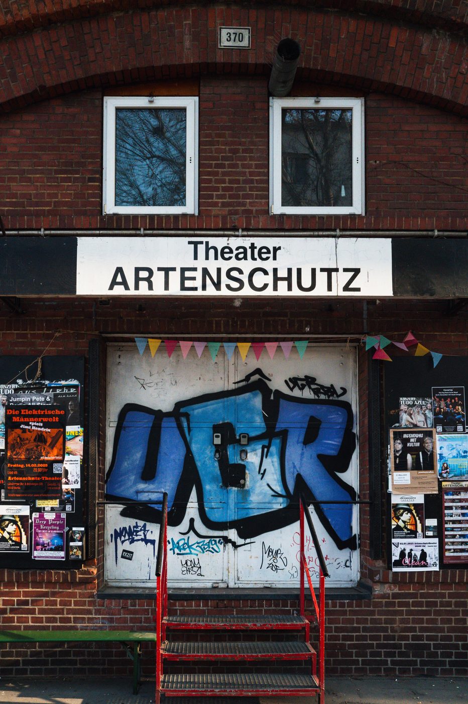 Facade of the Theater Artenschutz decorated with a blue tag and a string of pennants, Berlin