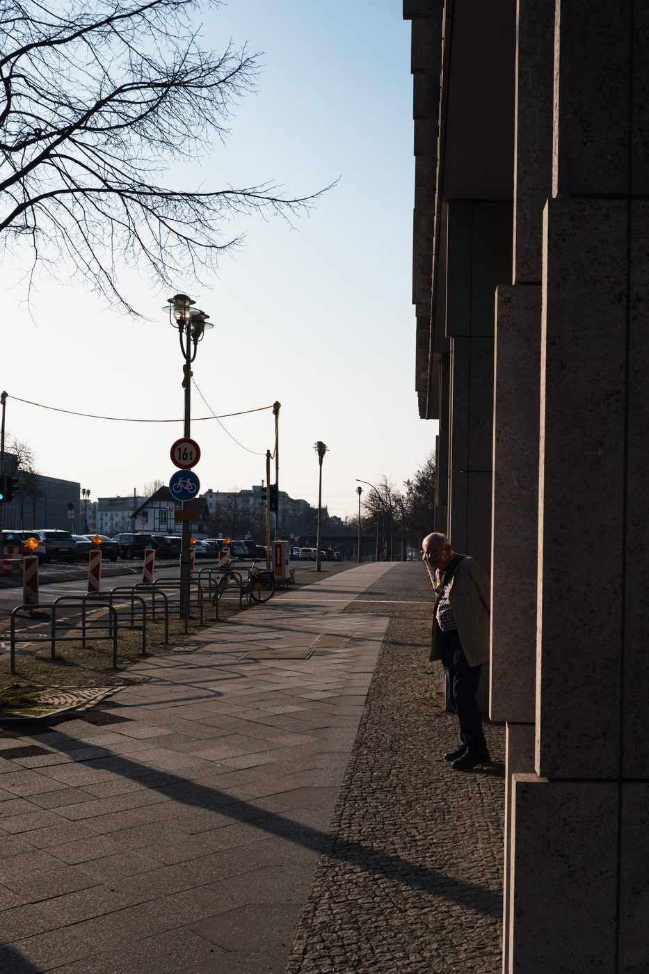 Elderly man leaning against the corner of a building at the end of the day, Berlin