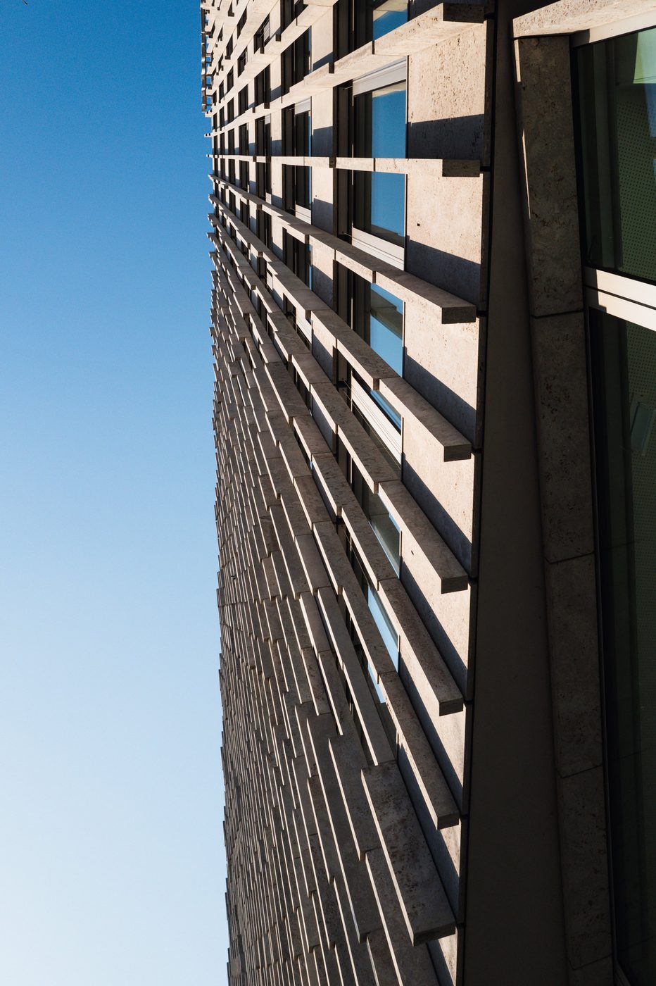 Low-angle view of the perforated, shadowed facade of a modern building, Berlin