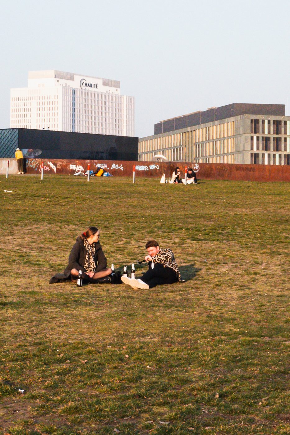 Couple picnicking on a lawn facing the Charité hospital tower, Berlin